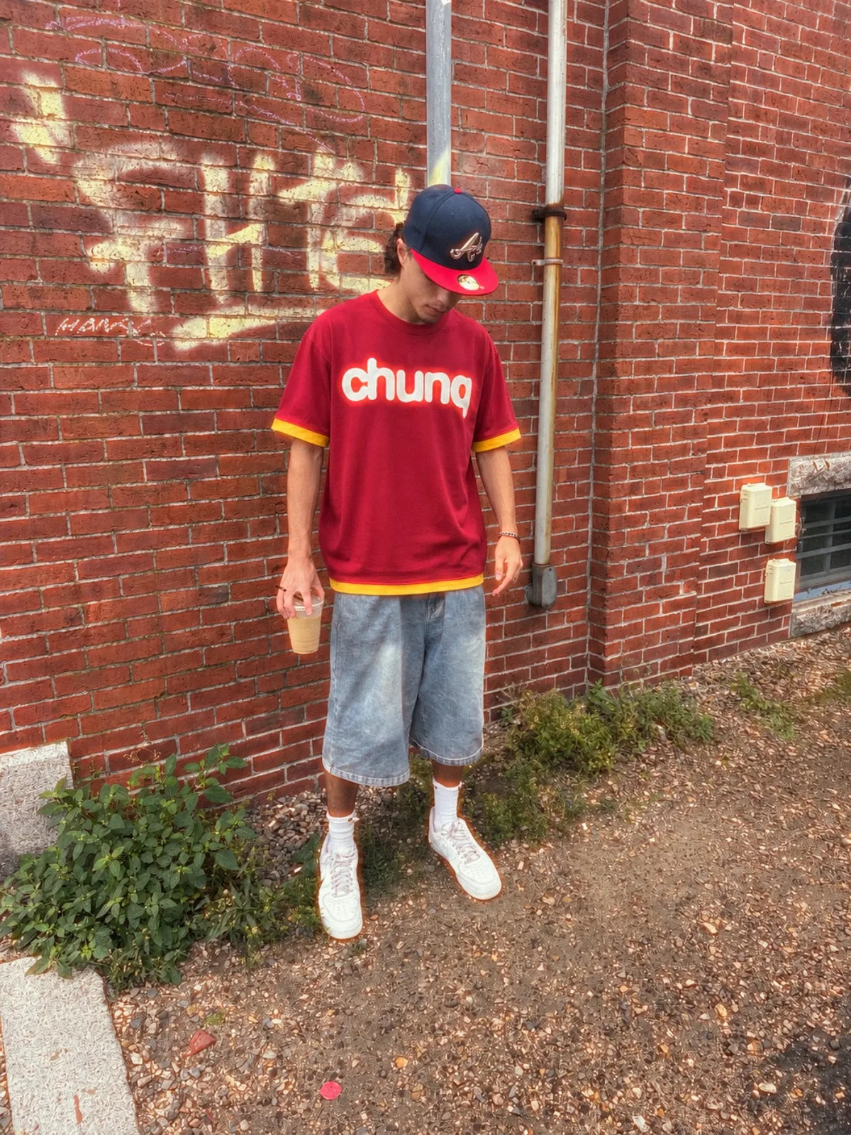 Model wearing a red Chunq jersey against a brick wall