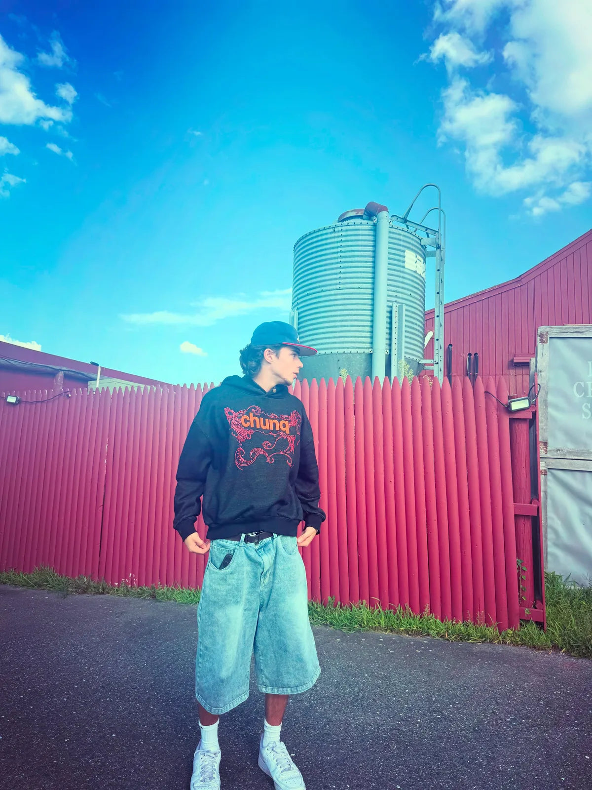 Model wearing a brown graphic Chunq hoodie under a blue sky